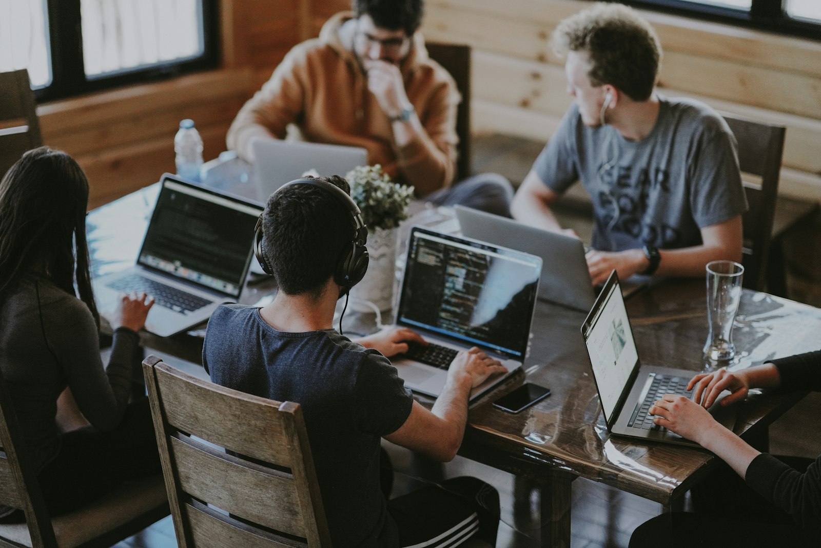 Team collaborating on laptops around a wooden table